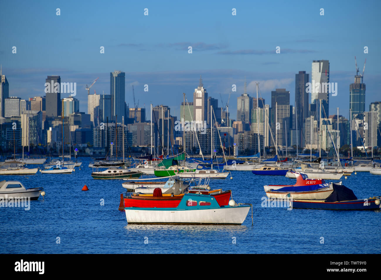 Barche colorate sulla Port Phillip Bay a Williamstown sul pomeriggio soleggiato con Melbourne skyline della città in background Foto Stock