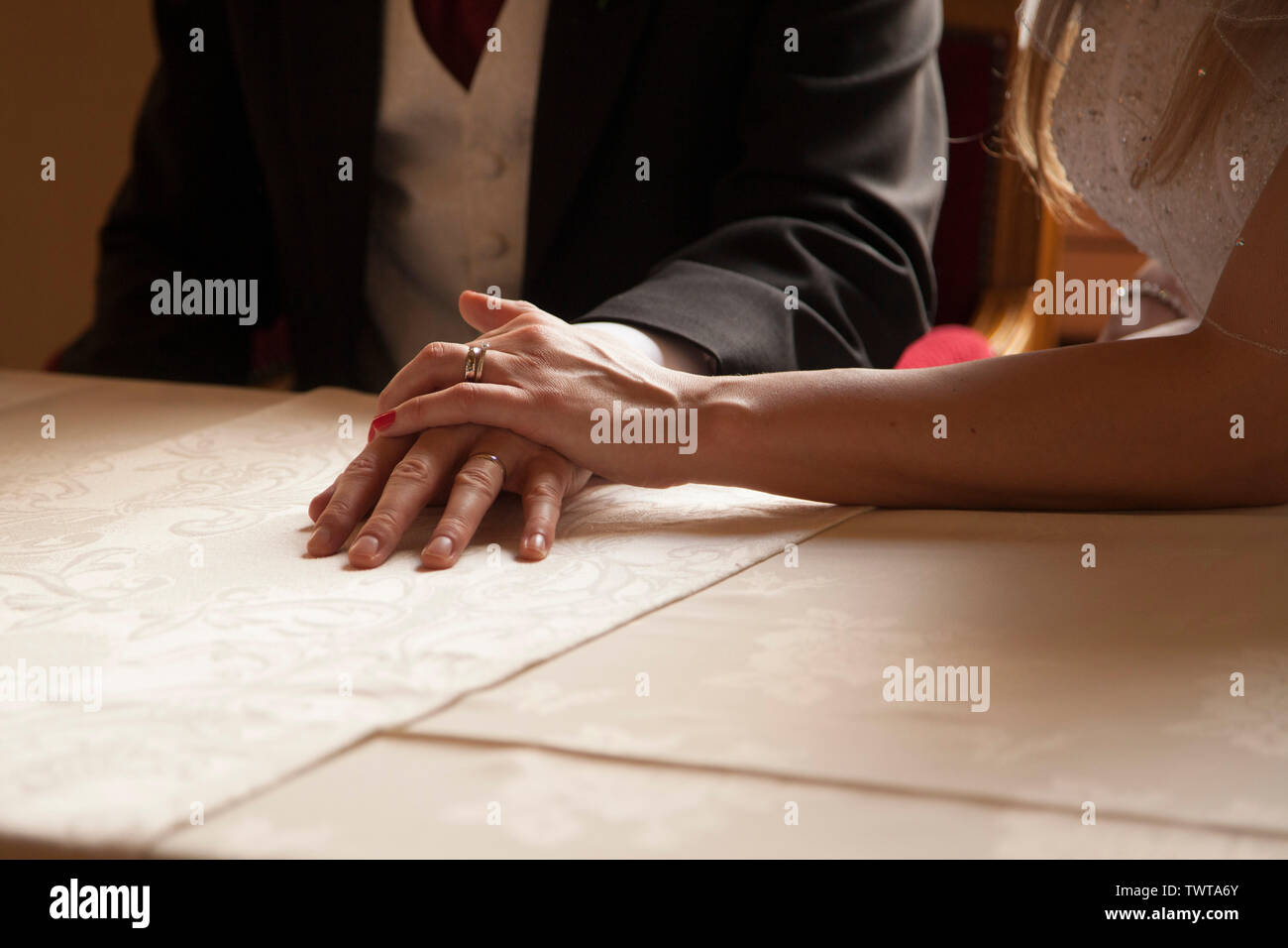 Sposi femmina e sposi maschio che tengono le mani sul tavolo mostrare gli anelli di nozze a colori con lo spazio di copia Foto Stock