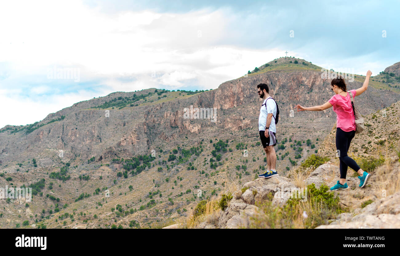 Orihuela, Spagna - 22 Giugno 2019: Gruppo escursioni nel paesaggio collinare contro il Cityscape di Orihuela. Le persone sane esercitare trekking a piedi una montagna. Foto Stock