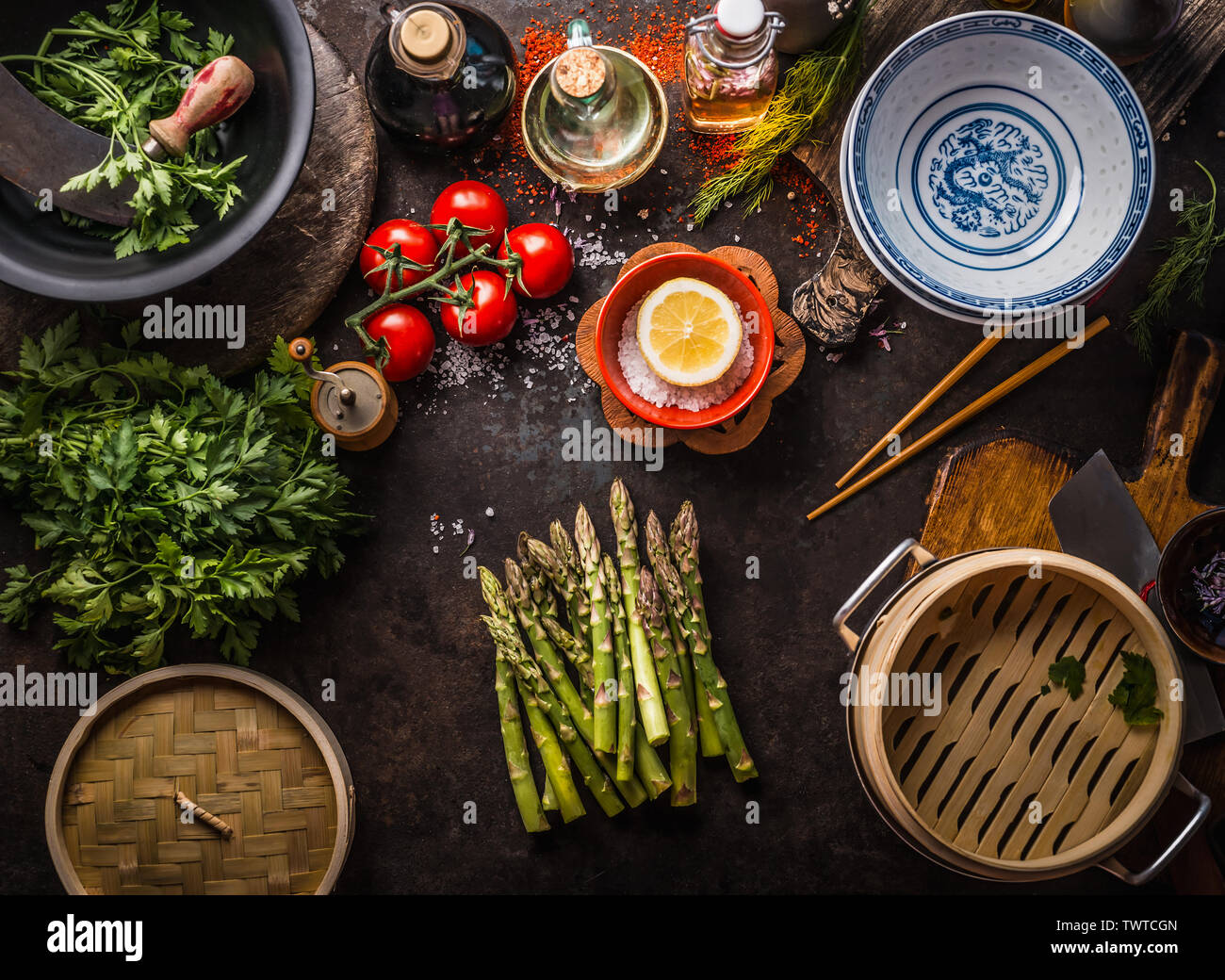 Gli asparagi verdi mazzetto , bambù asiatico vaporizzatore ed ingredienti freschi e saporiti per vegetariani sani mangiare e cucinare in stile asiatico sul tavolo rustico con Foto Stock