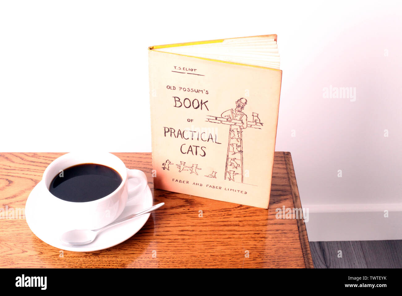 Possums vecchio libro di pratica Gatti - un libro di poesie di T.S. Eliot con una tazza di caffè nero su un tavolo da caffè in legno con sfondo bianco Foto Stock