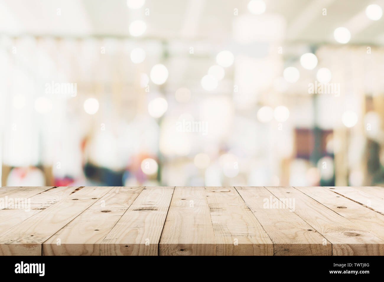 Svuotare tavolo in legno e sfondo sfocato - Store di shopping mall blur sullo sfondo bokeh con display montage per prodotto. Foto Stock