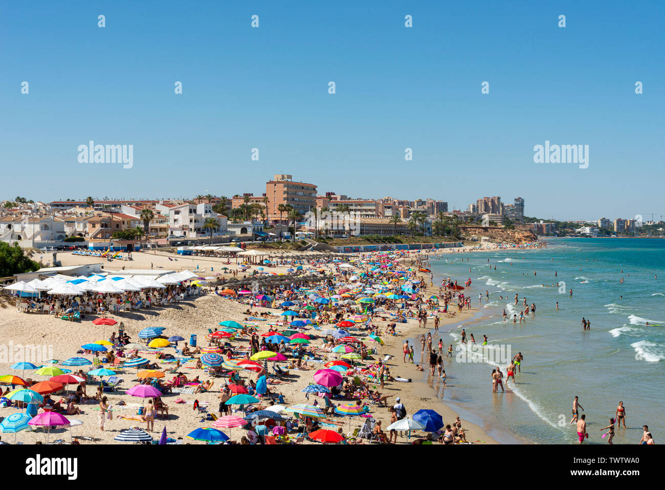 Occupato Mediterranean Beach a Playa Mil Palmeras, Pilar de la Horadada, Alicante, Spagna, Europa. Sun colorate sfumature di blu del cielo e del mare. Costa Blanca Foto Stock