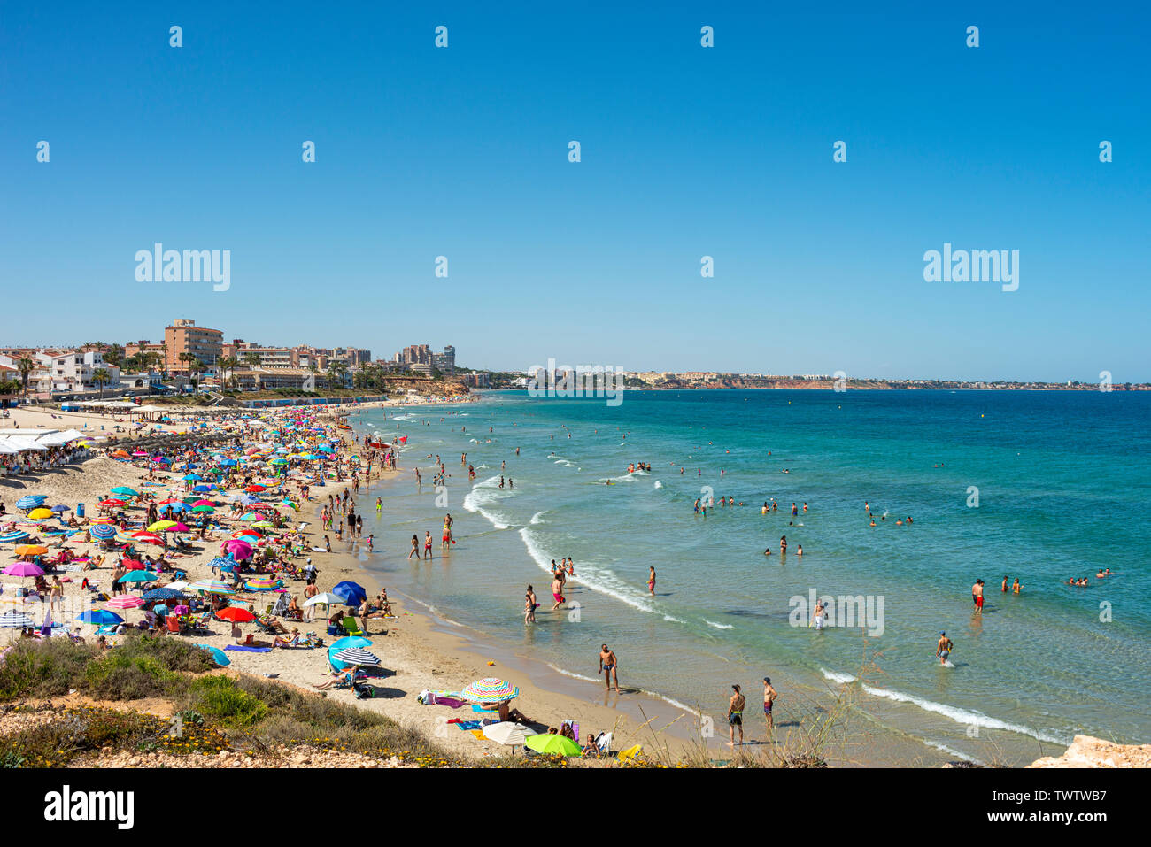 Occupato Mediterranean Beach a Playa Mil Palmeras, Pilar de la Horadada, Alicante, Spagna, Europa. Sun colorate sfumature di blu del cielo e del mare. Costa Blanca Foto Stock