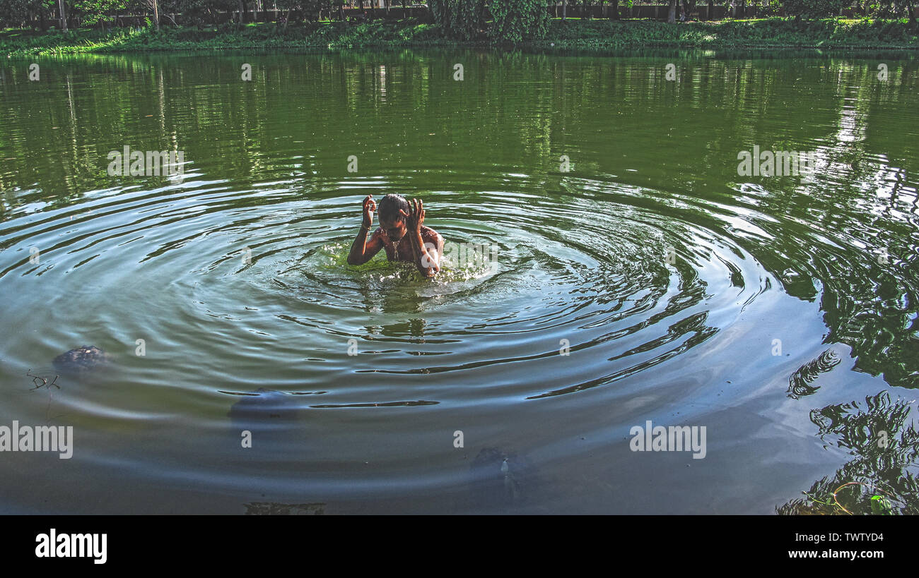 Estate ramna parco 23 giu,2019 Dhaka bangladesh.a uomo sta facendo un bagno nello stagno del parco ramana a causa di esaurimento del calore.Nazmul Islam / alamy stock vivere Foto Stock