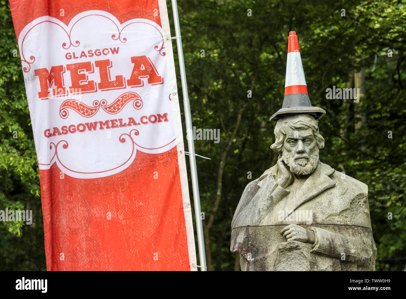 Glasgow, Regno Unito. Il 23 giugno 2019. La Scozia il più grande evento multiculturale ha avuto luogo a Kelvingrove Park, Glasgow con la musica, il teatro e la cultura di tutto il mondo. Glasgow Mela iniziò nel 1990 come parte della città celebrazioni come Città Europea della Cultura e presenta artisti, musicisti e gruppi locali da Glasgow di diverse comunità e viene visto come la vetrina del contemporaneo multiculturale di Scozia. Glasgow tradizionale cono stradale messo sulla parte superiore della statua al sociologo e storico Thomas Carlyle all'entrata di Kelvingrove Park Credit: Findlay/Alamy Live News Foto Stock