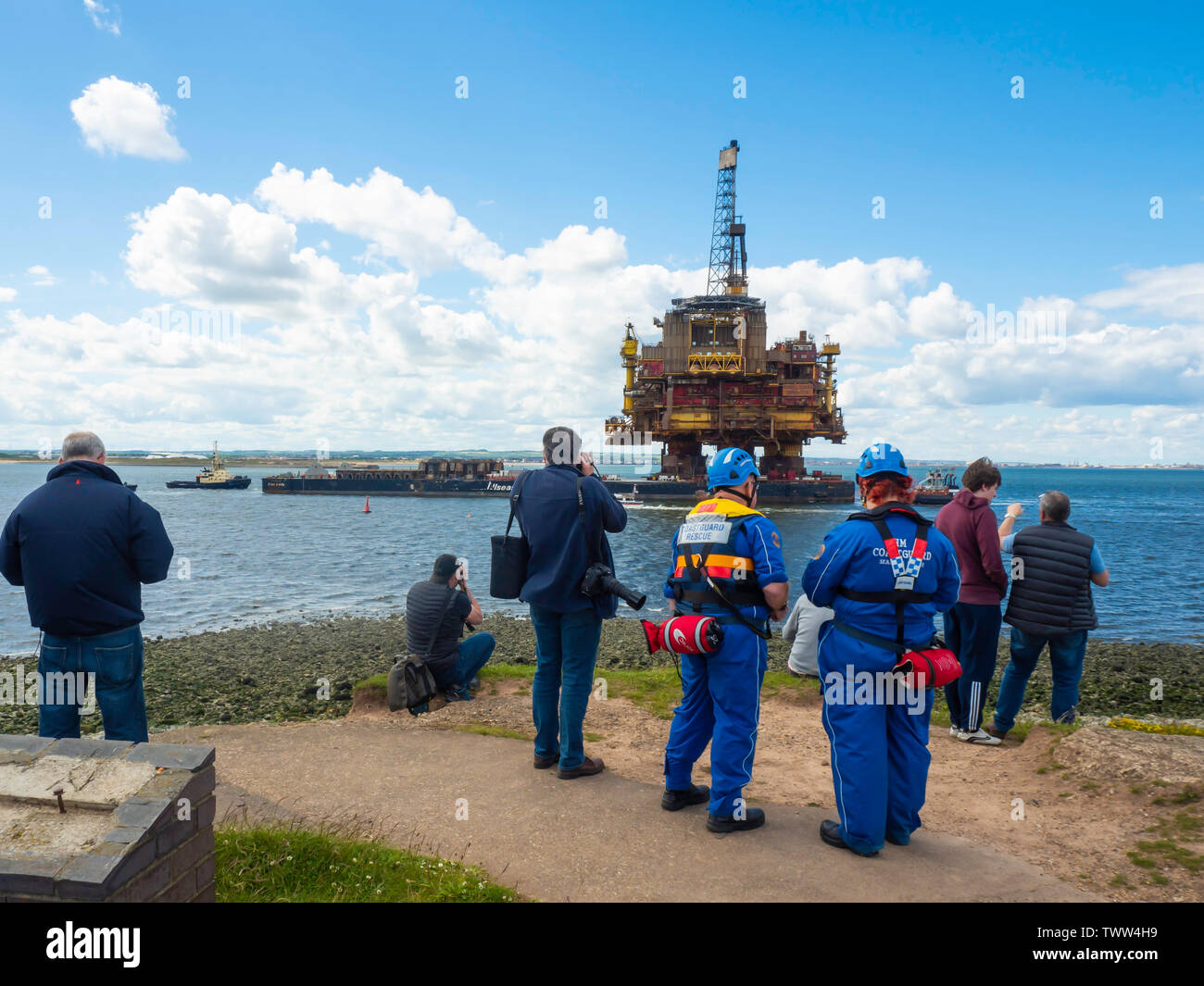 Spettatori fotografi e guardie costiere guarda il mazzo di Shell/Esso Brent Bravo platform che arrivano nel Fiume Tees dopo 40 anni nel Mare del Nord Foto Stock
