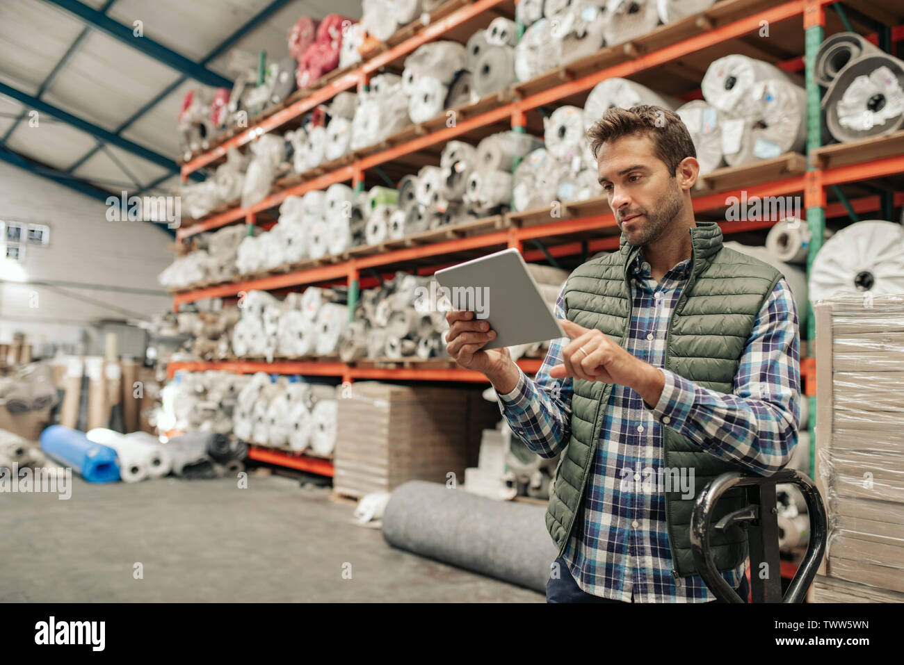 Lavoratore di magazzino utilizzando una tavoletta digitale per verificare le scorte Foto Stock