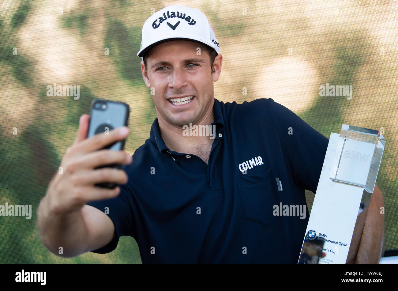 Eichenried, Germania. Il 23 giugno, 2019. Golf: Tour Europeo - International Open, single, uomini, 4° round. Professionista di Golf Andrea Pavan dall'Italia detiene il suo trofeo in una mano dopo la sua vittoria, e rende un selfie con gli altri con un telefono cellulare. Credito: Sven Hoppe/dpa/Alamy Live News Foto Stock