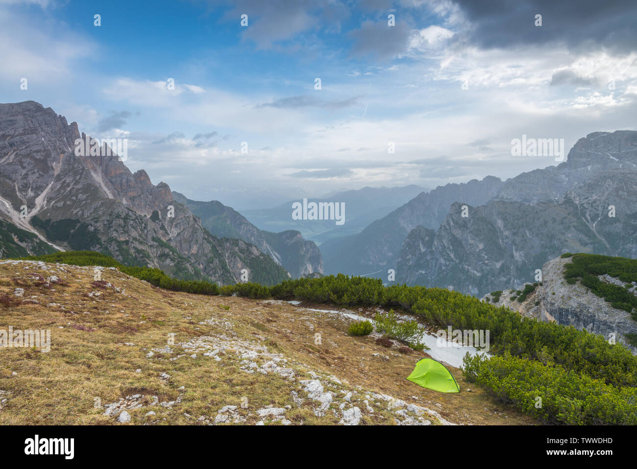 Campeggio da solista con una solitaria, verde Berghaus tenda in alto paese alpino dell'Italia Dolomiti. Campeggio selvaggio in cima a una montagna. 'S tenda singola. Foto Stock