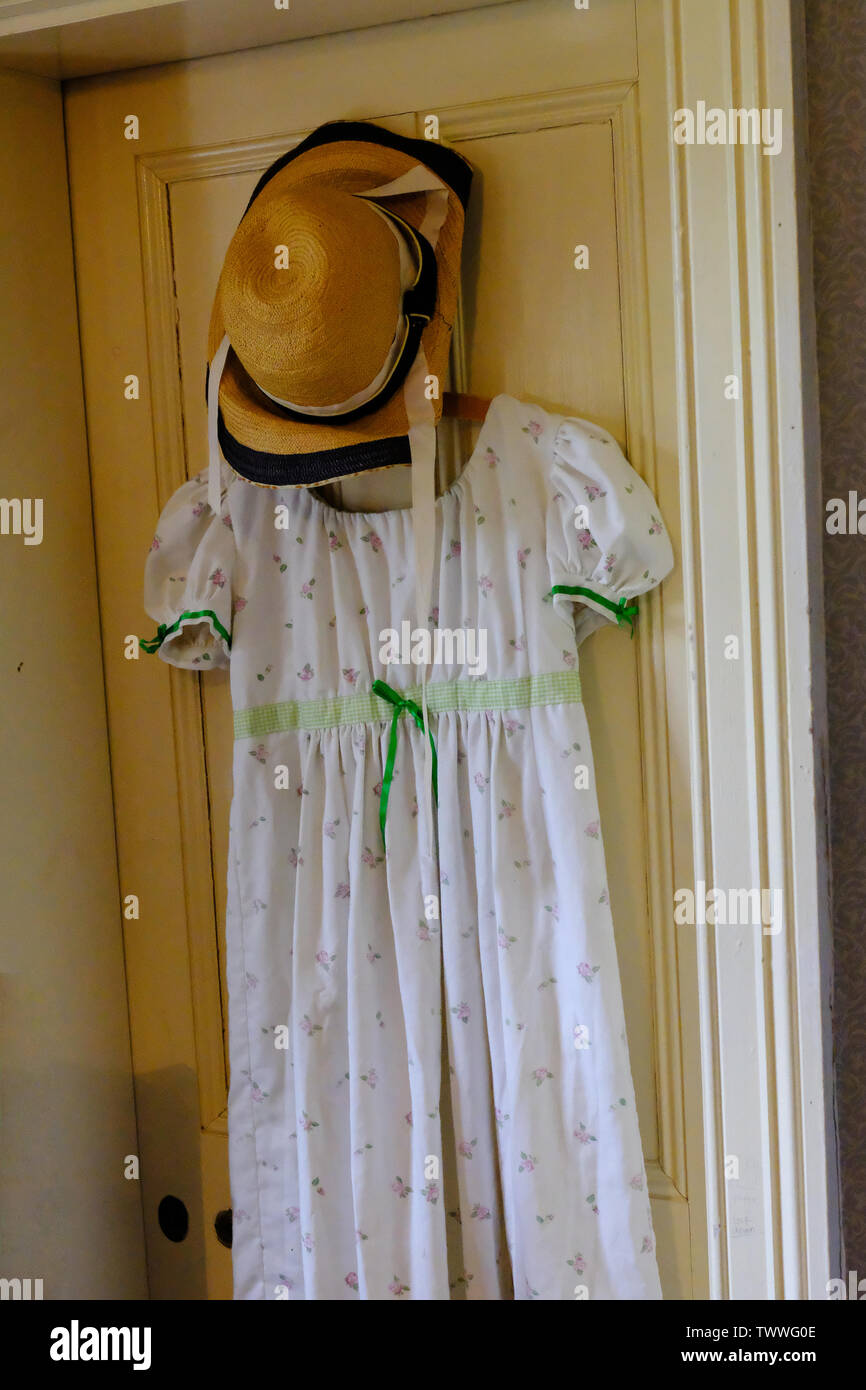 Un cotone vittoriano abiti estivi e cappello di paglia appeso sul retro di una porta - Giovanni Gollop Foto Stock