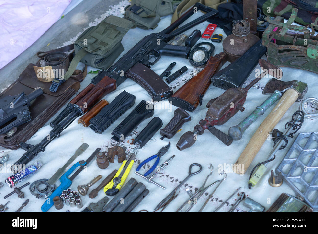 Antiquariato antichi sono venduti in un mercato delle pulci.una copia di Kalashnikov fucile da assalto sul bancone lungo con vari strumenti Foto Stock