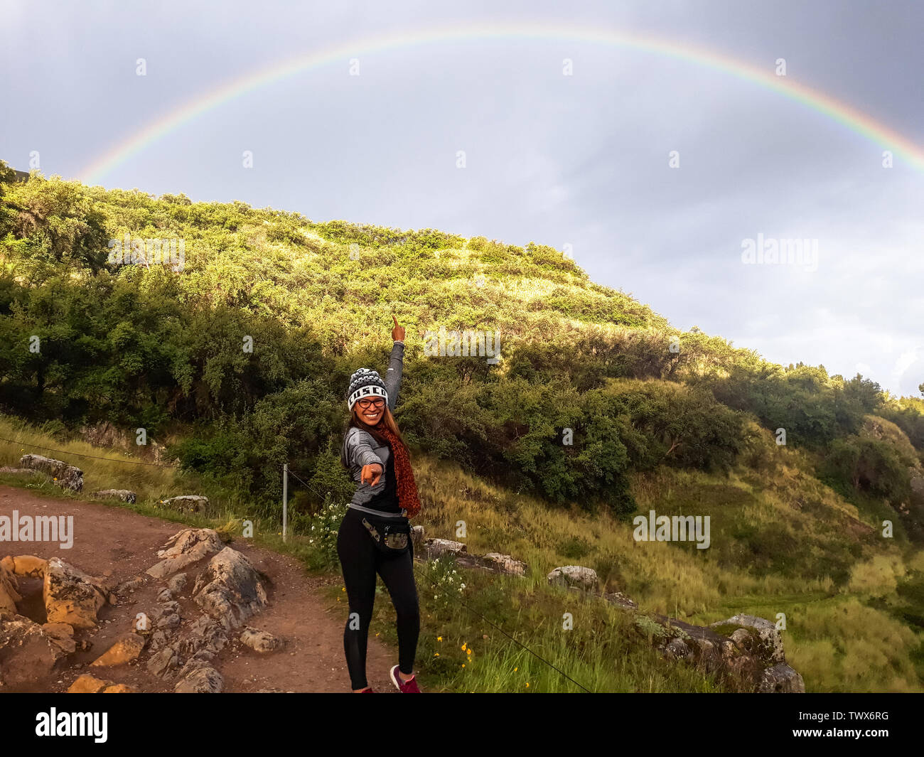 Seguire il concetto del vostro sogno. Una donna che cammina sul sentiero di montagna e rivolta verso l'arcobaleno nel cielo. Foto Stock