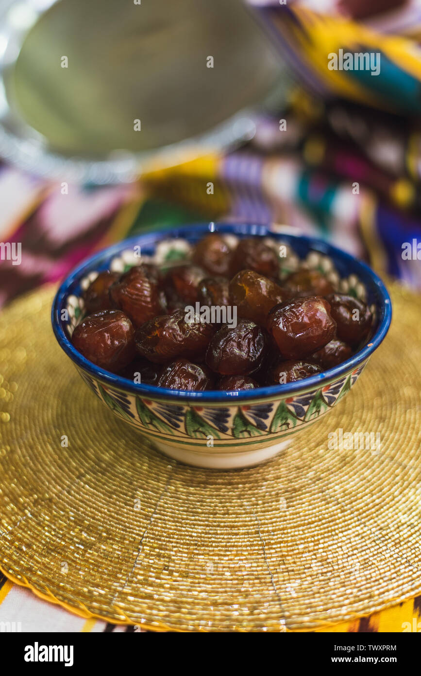 I dolci orientali nei piatti del Medio Oriente con oro e sul panno tartara. Dolce essiccato date giacciono su una piastra su una tovaglia d'oro. Foto Stock