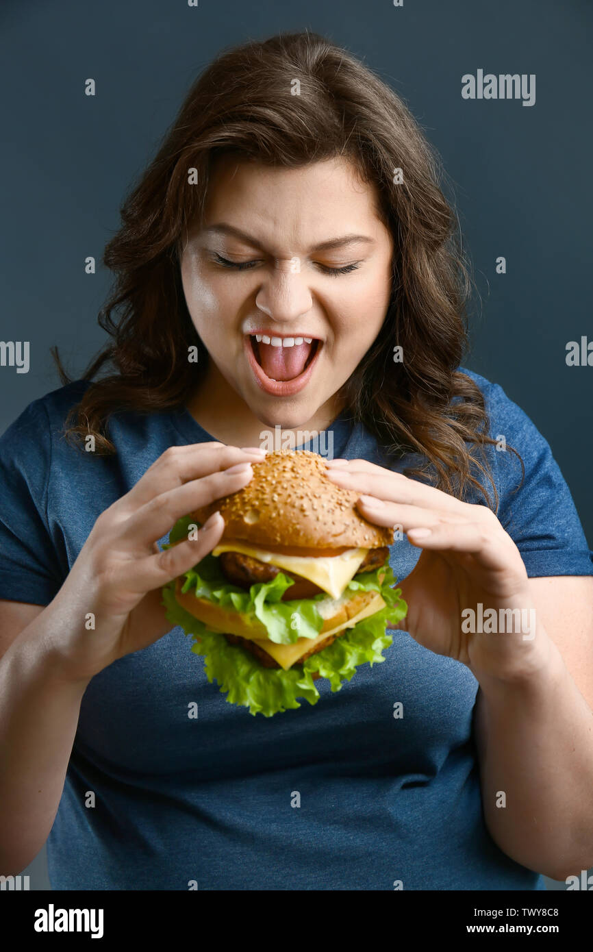 Taglie donna con gustosi burger su sfondo grigio. Concetto del corpo positivo Foto Stock