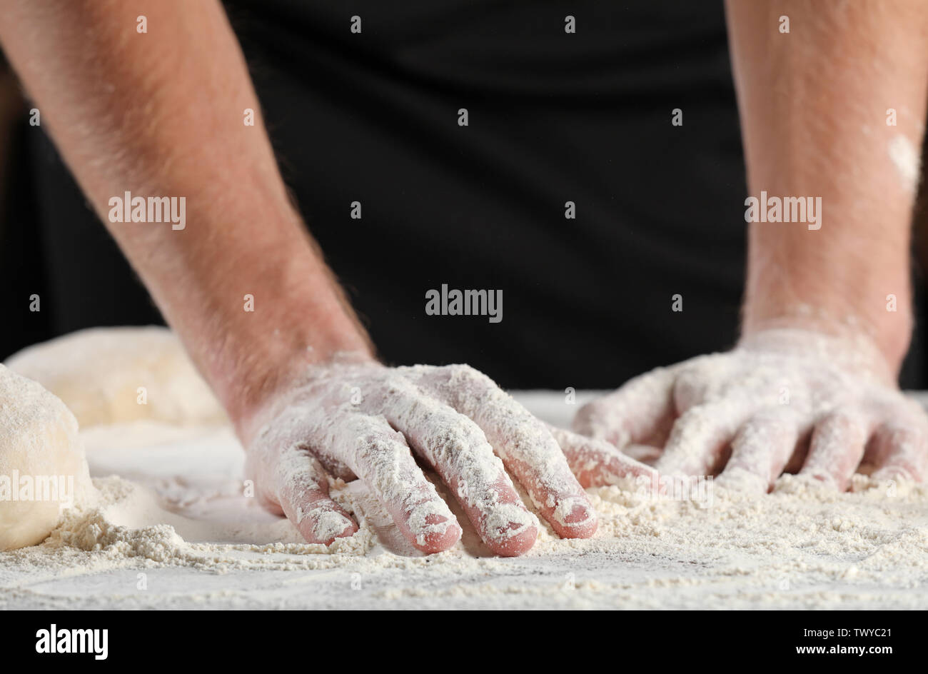 Uomo con le mani nella farina su sfondo scuro, primo piano Foto Stock