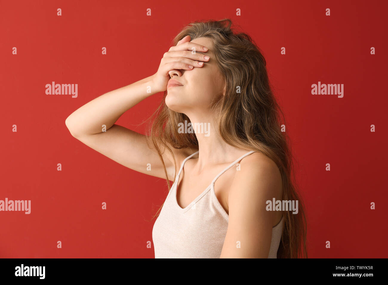 Giovane donna che copre la sua gli occhi sul colore di sfondo Foto Stock