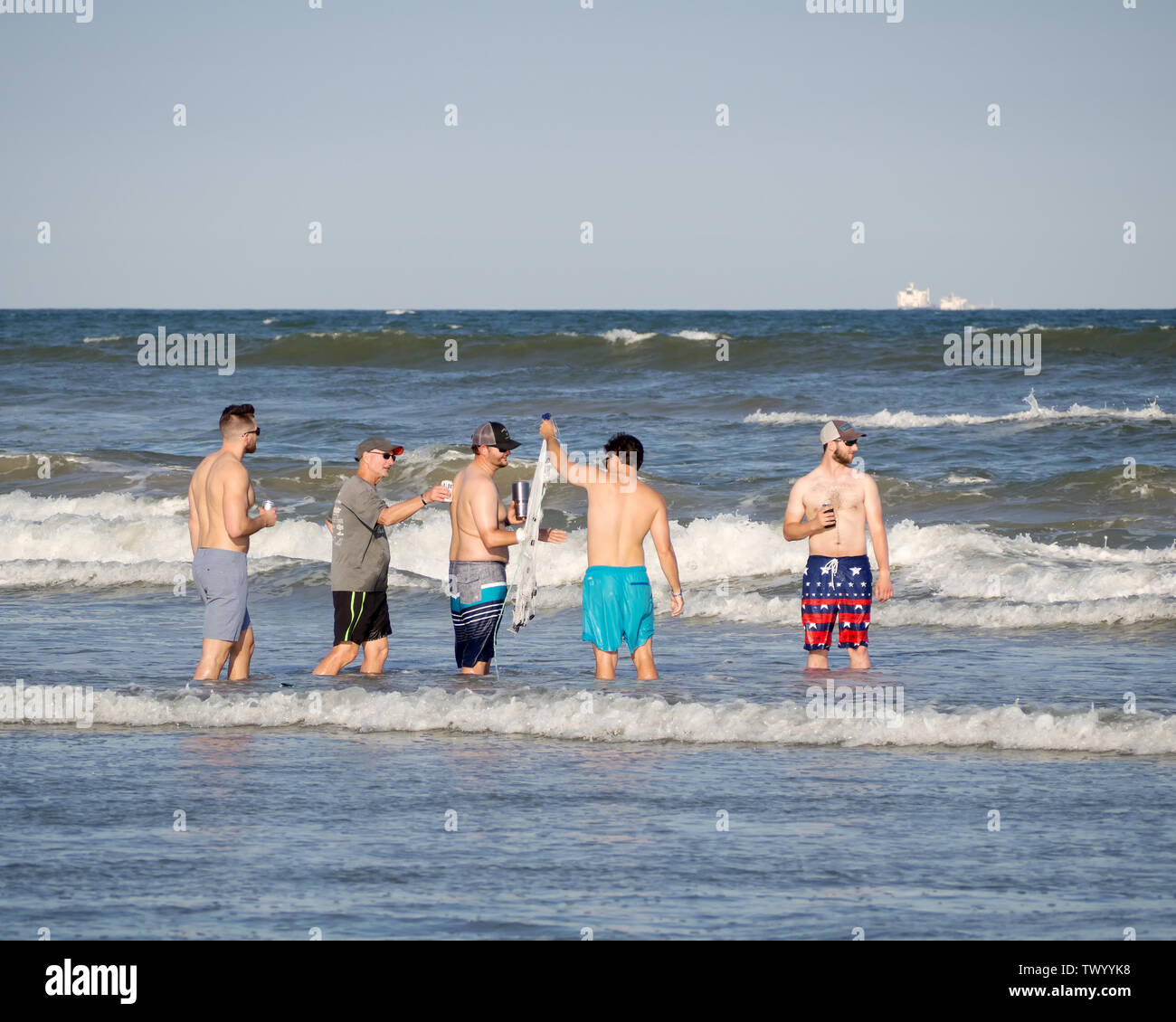 Un gruppo di uomini con un cast net socializzazione in Mustang Island surf. Port Aransas, Texas, Stati Uniti d'America. Foto Stock