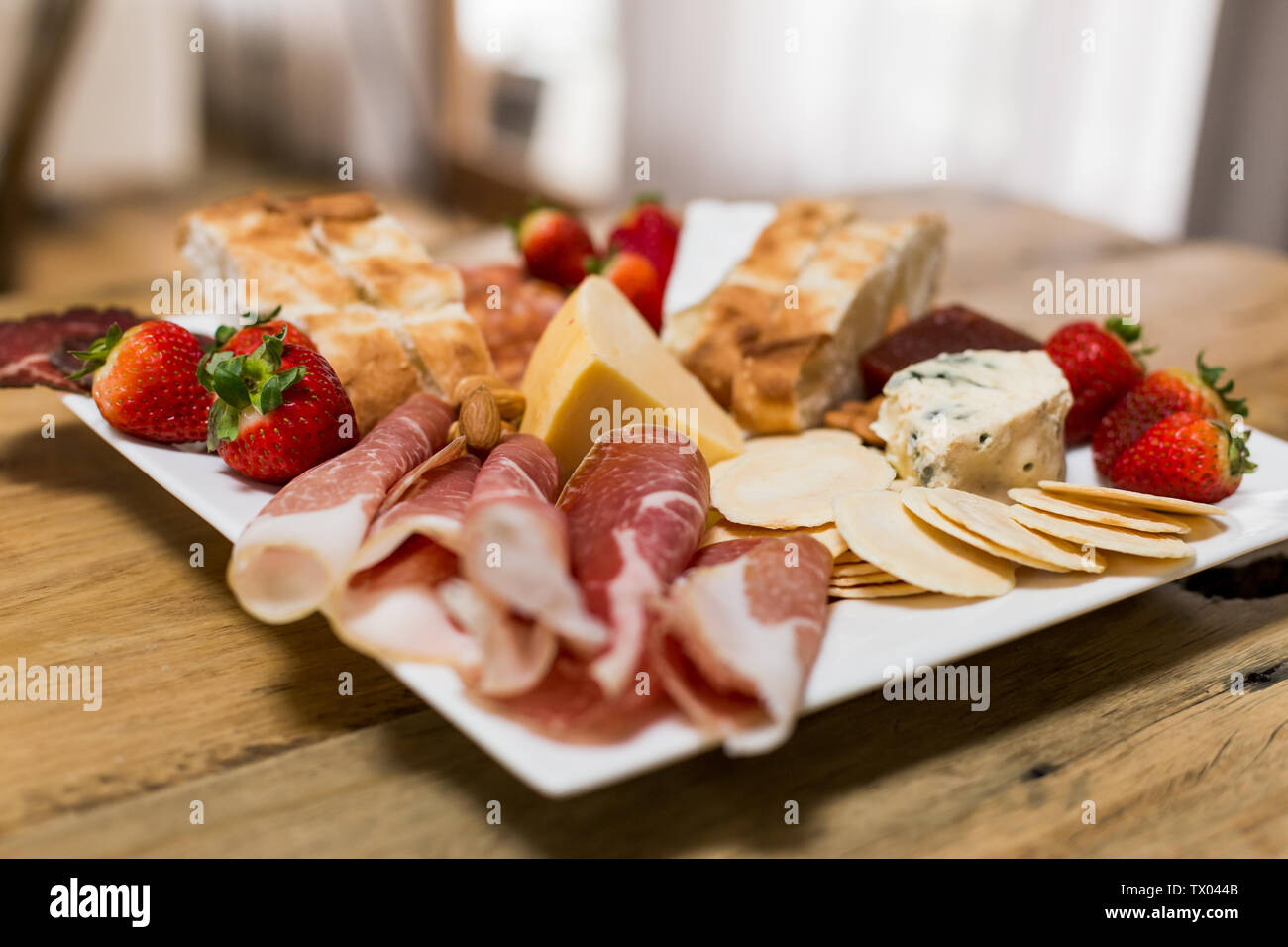 Antipasto piatto con una miscela di affettati, fragole, crackers, formaggio e pane Foto Stock