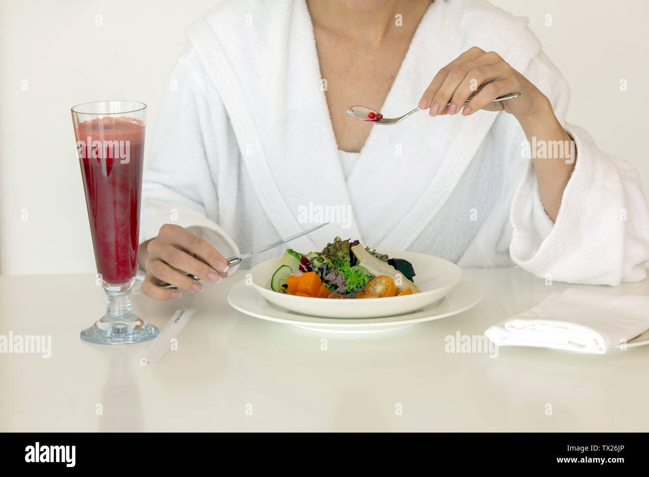 Donna in tunica bianca insalata mangiare a tavola Foto Stock