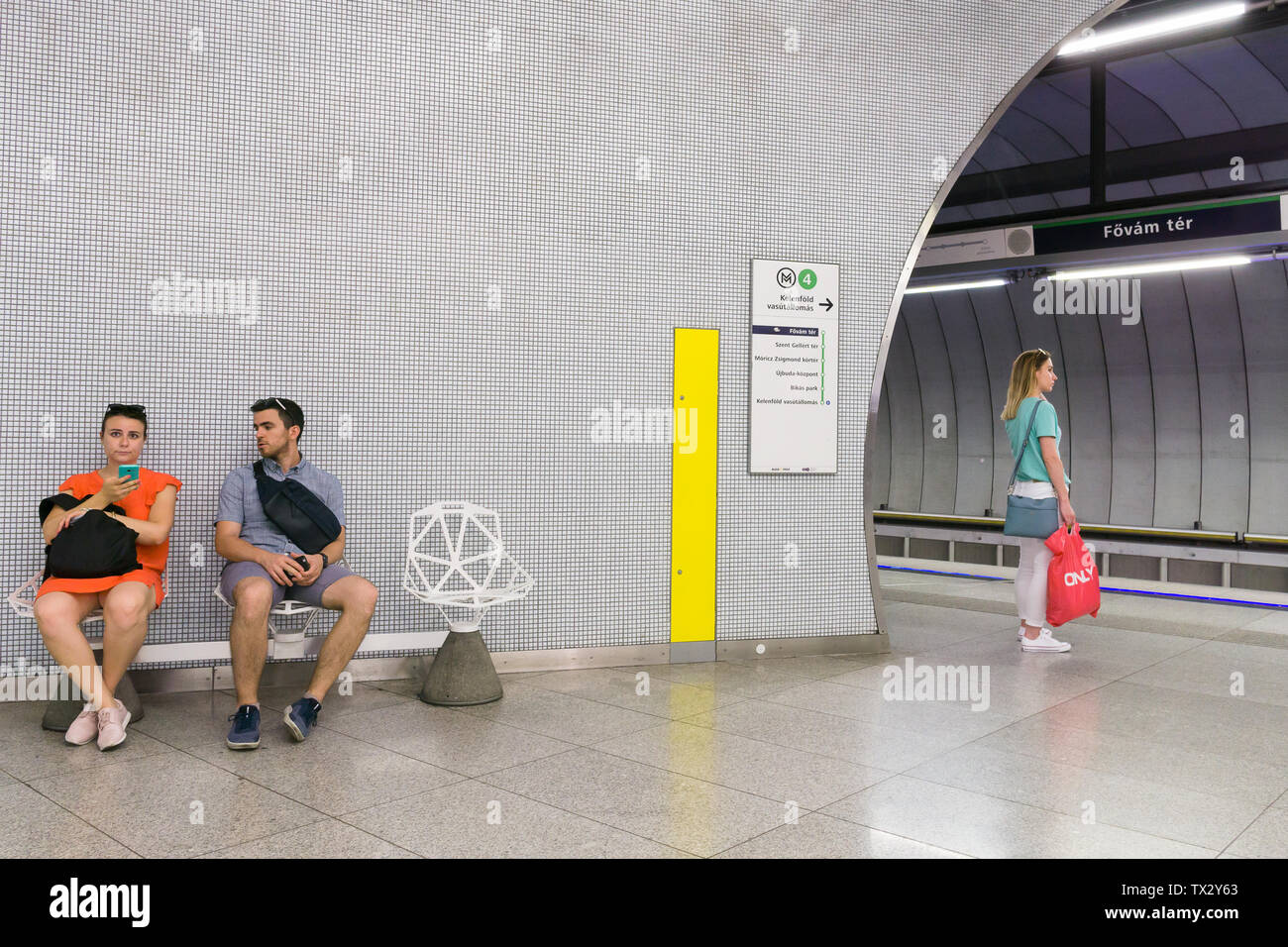 I passeggeri in attesa di un treno in Fovam ter stazione della metropolitana sulla M4 Linea di Budapest, Ungheria. Foto Stock