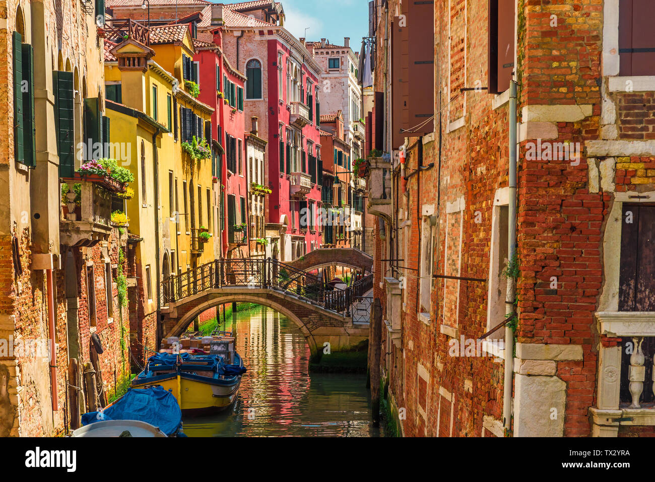 Canale veneziano con ponte di barche e le variopinte facciate delle vecchie case medievali a Venezia, Italia nella giornata di sole Foto Stock