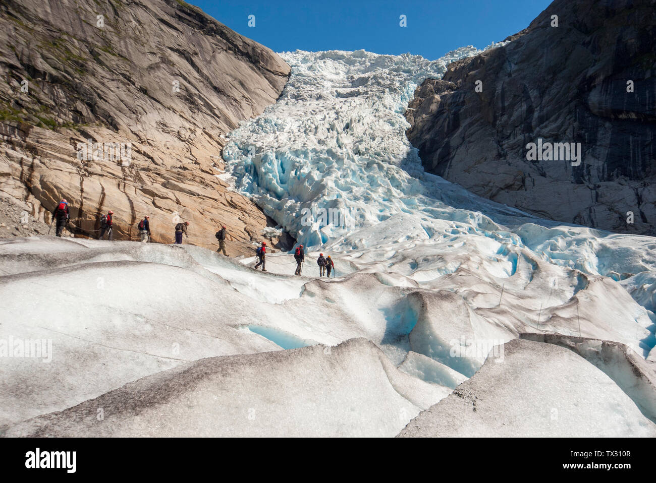 I turisti a camminare su un ghiacciaio guidato tour sul Ghiacciaio Briksdal in Norvegia Foto Stock