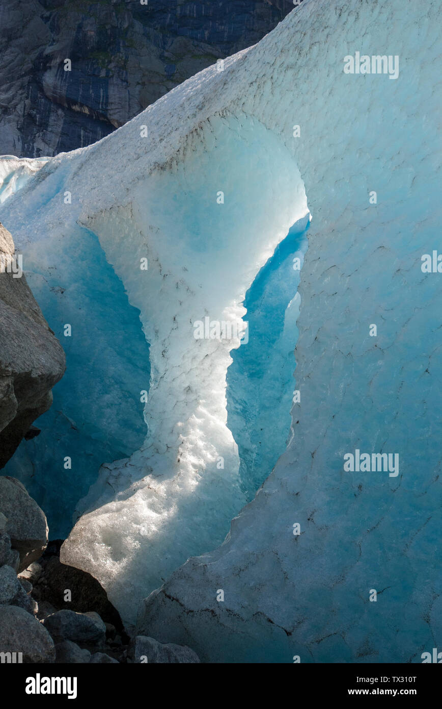 Un grande buco in un ghiacciaio con ghiaccio fondente e la caduta di gocce d'acqua, Ghiacciaio Briksdal, Norvegia Foto Stock