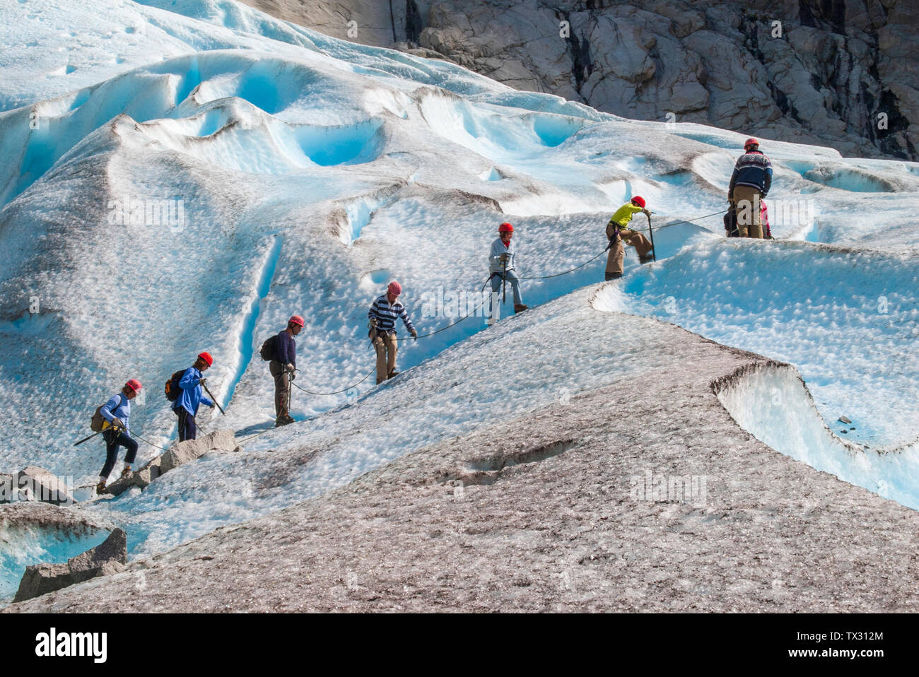 I turisti a camminare su un ghiacciaio guidato tour sul Ghiacciaio Briksdal in Norvegia Foto Stock