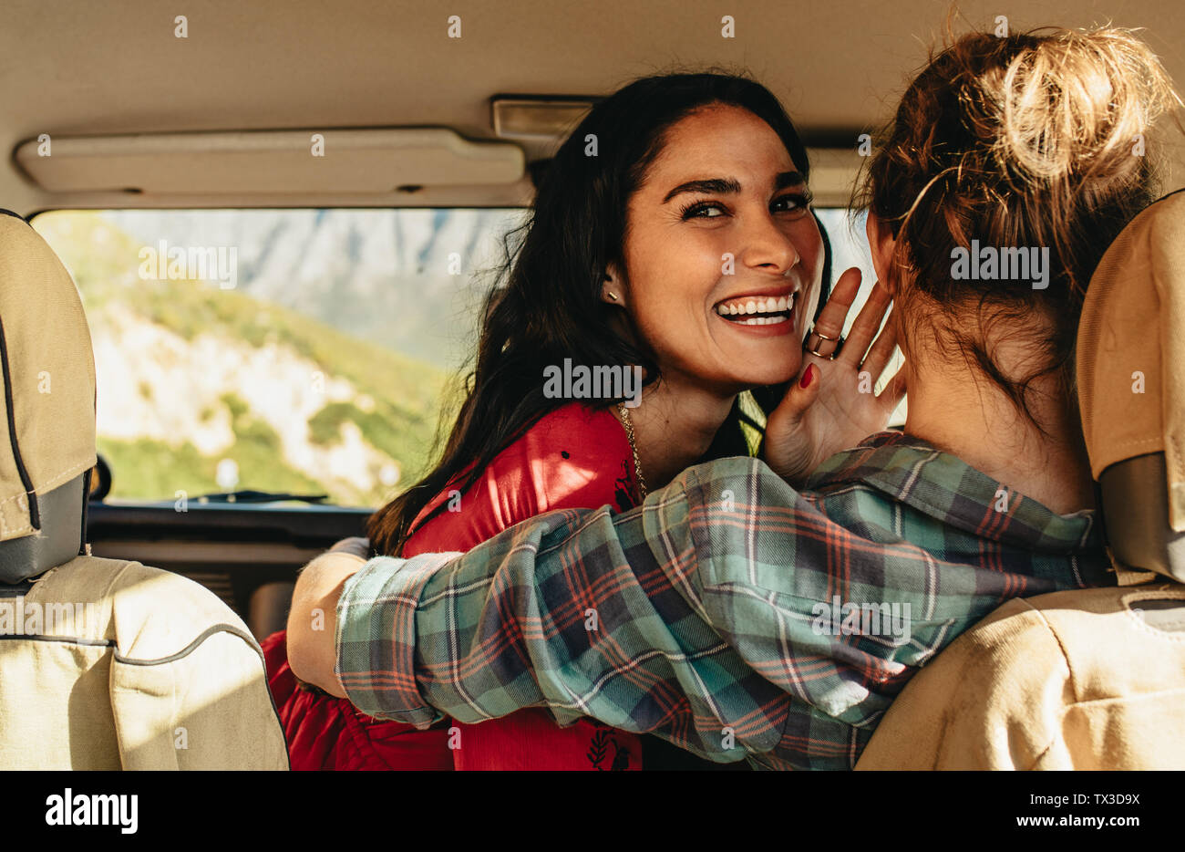 Sorridente giovane donna che abbraccia il suo ragazzo alla guida di una vettura. Amare giovane in un auto in vacanza. Foto Stock