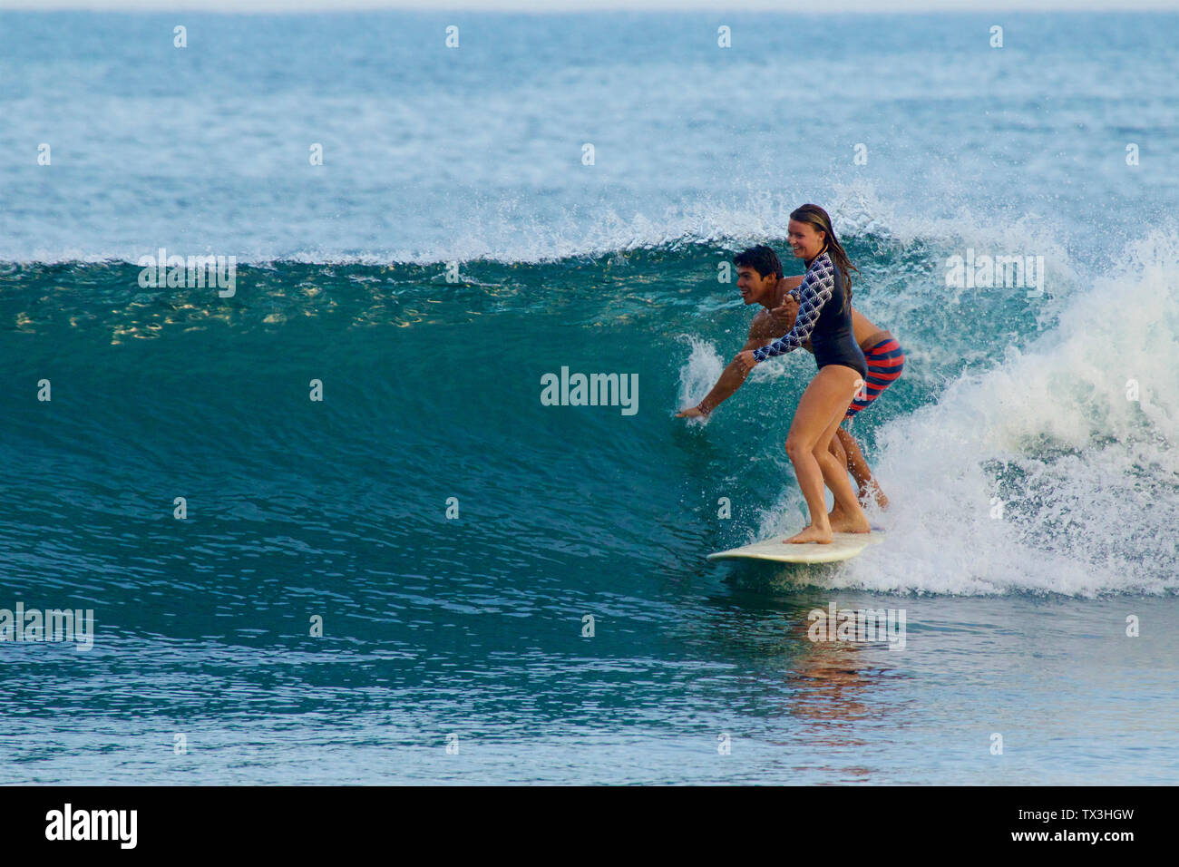 Coppia giovane la condivisione con la tavola da surf, surf onde oceaniche Foto Stock