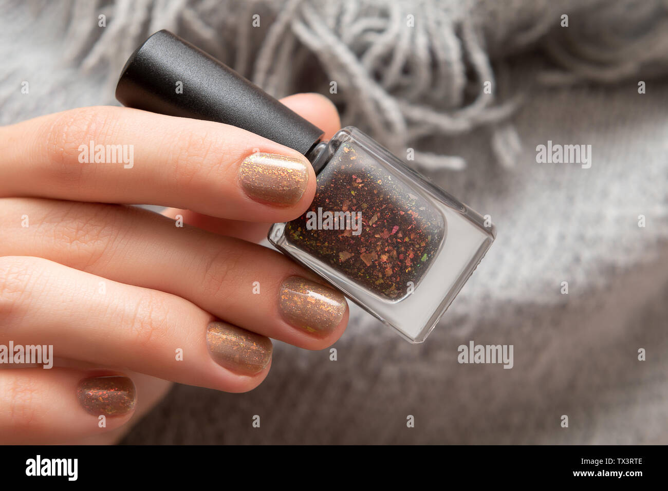 Mano femmina con glitter nail design azienda Nail Polish bottiglia Foto Stock