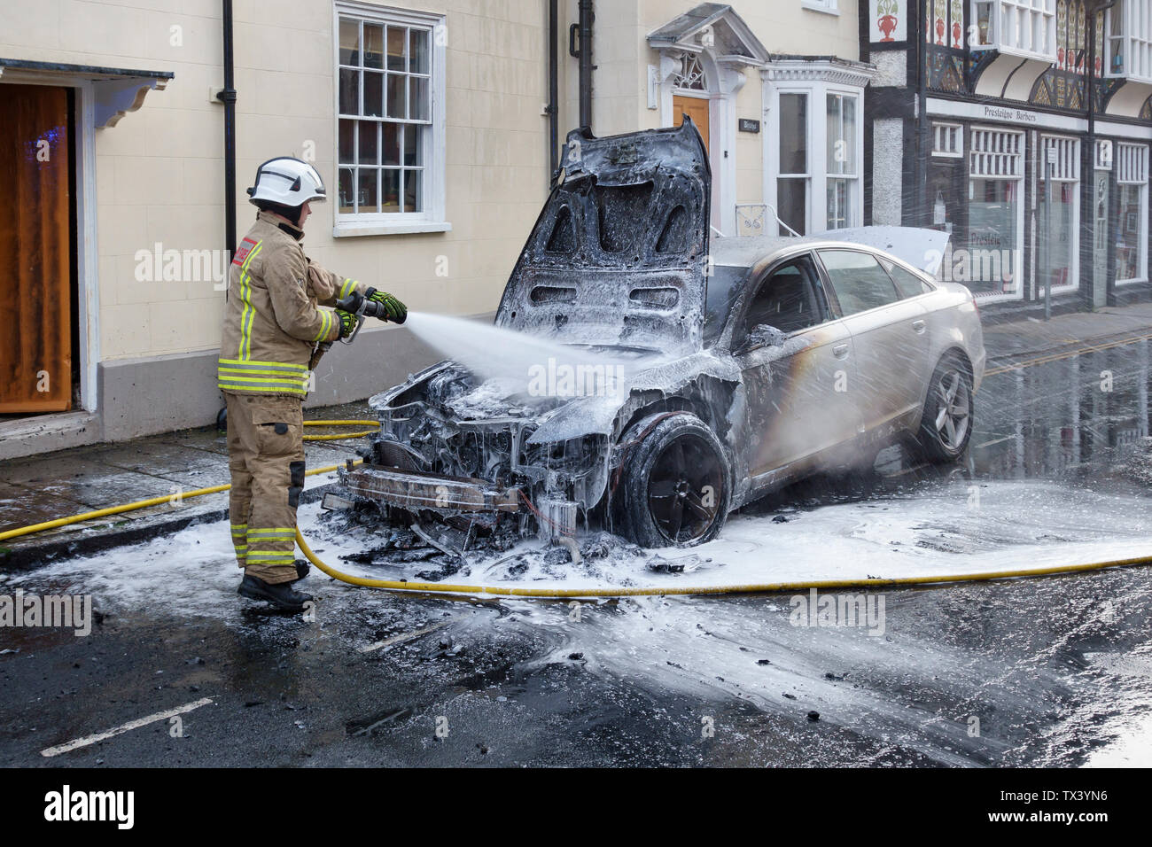 Un membro della metà e West Wales Fire e servizio di soccorso estinzione di un incendio auto in Presteigne, Powys, Wales, Regno Unito Foto Stock