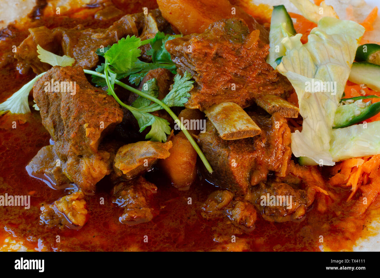 Un curry di montone roti con sambals - un iconico Durban pasto composto da un roti condito con curry di montone e sugo di carne. Il sambals sono carote grattugiate con c Foto Stock