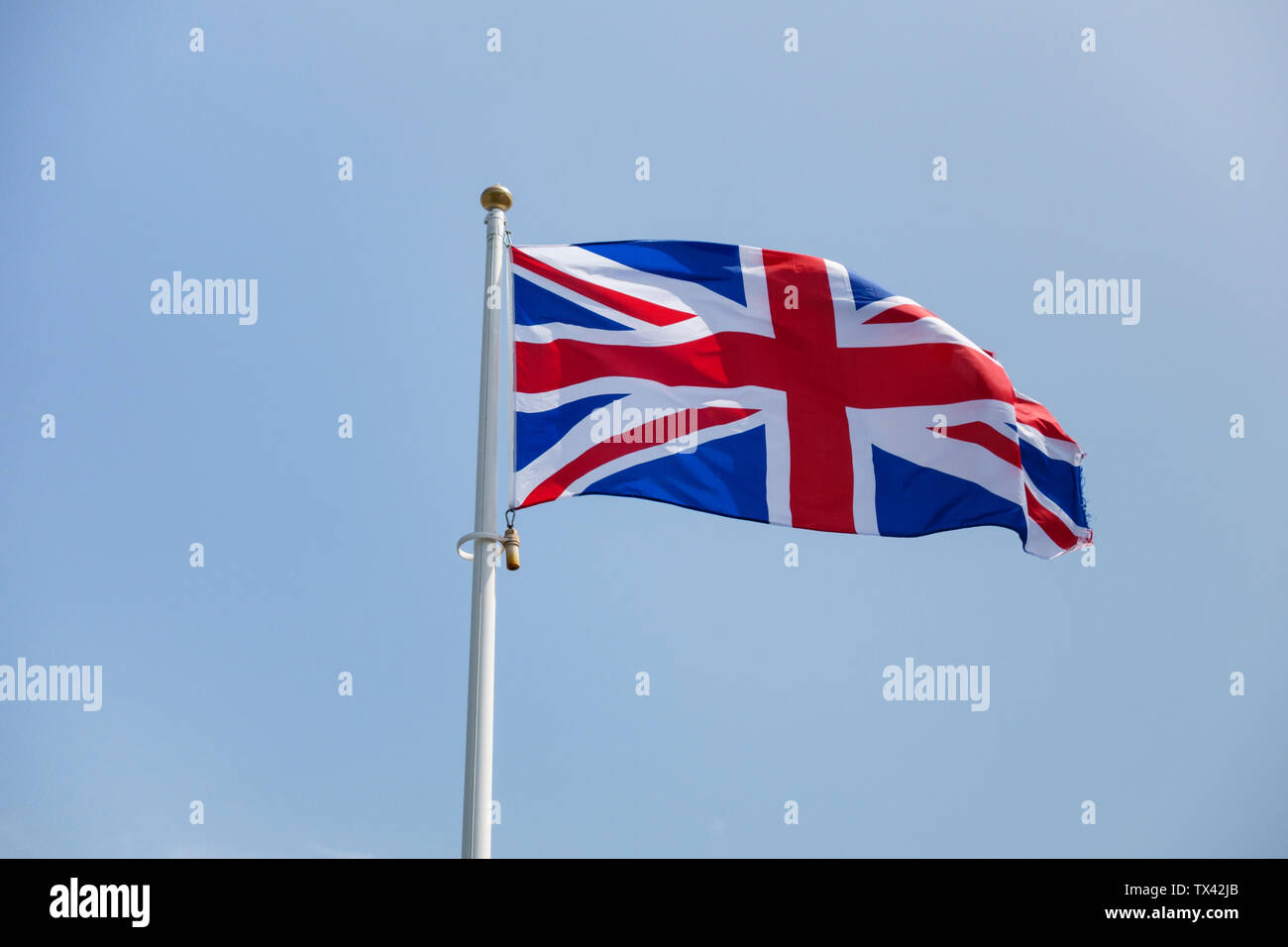 Il British National flag (spesso erroneamente chiamato l'Unione Jack) battenti contro un chiaro Cielo di estate blu Foto Stock