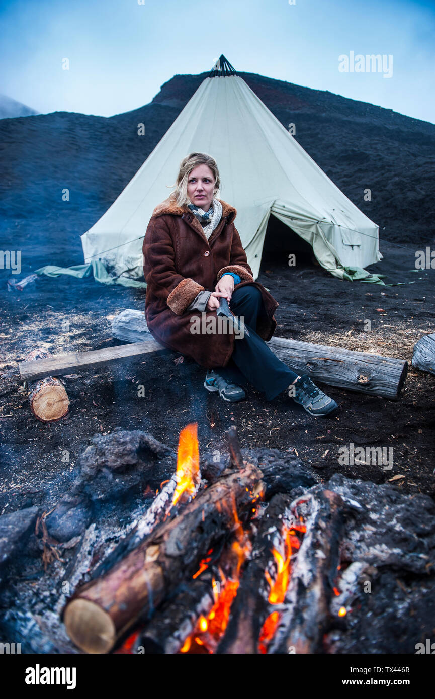 Donna in pelliccia giacca in piedi davanti a una tenda tende Tepee prima che il vulcano Tolbachik, Kamchatka, Russia Foto Stock