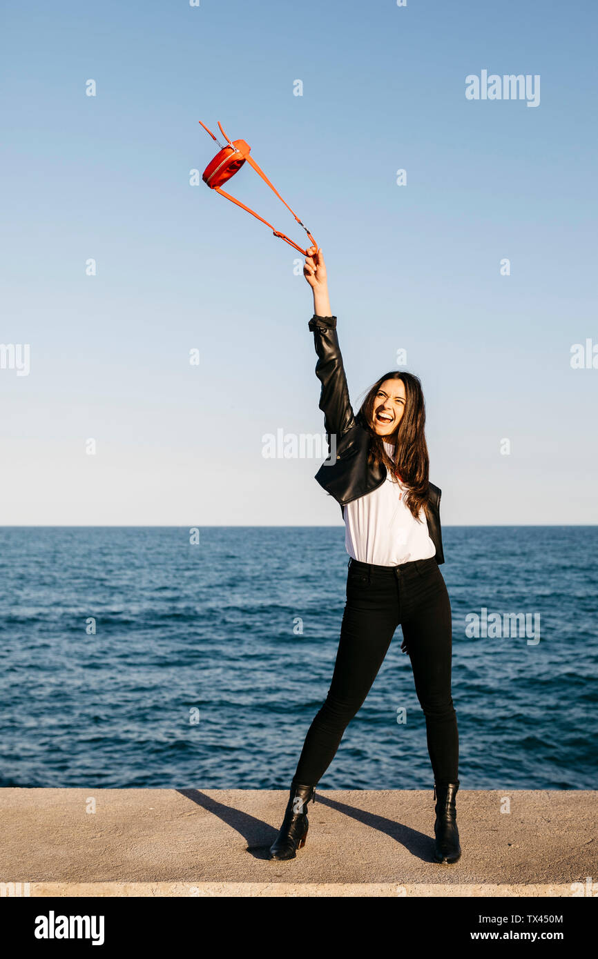 Donna felice giocando con il sacchetto rosso, il mare in background Foto Stock