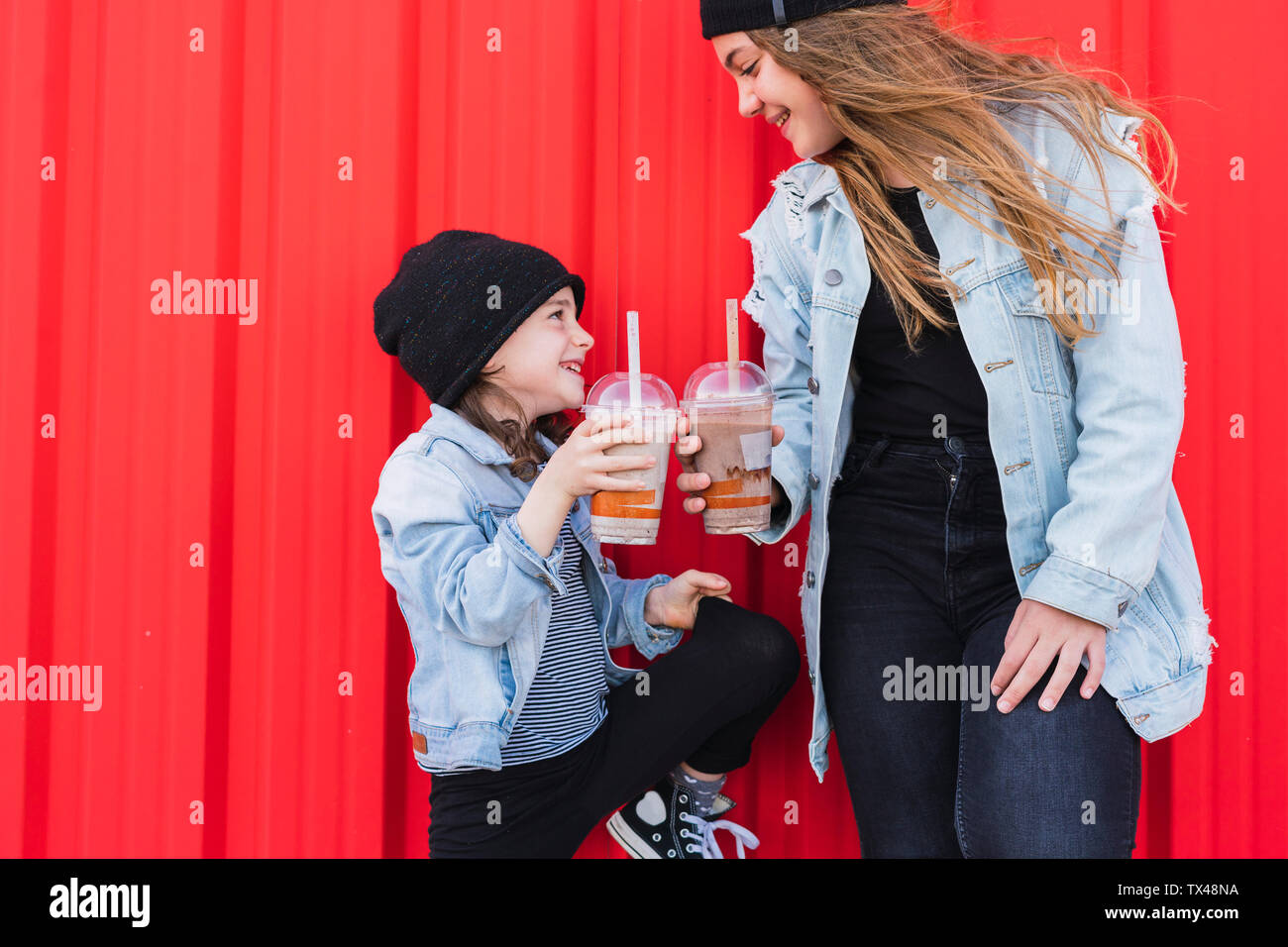 Ragazza adolescente e sorellina tostare con bevande Foto Stock
