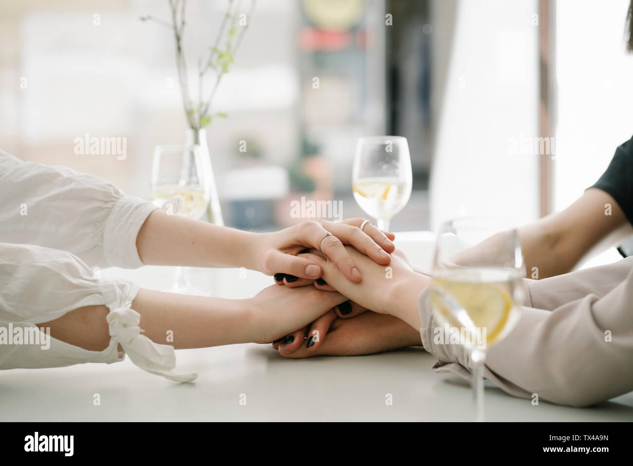 Close-up di tre donne mani di impilamento sulla tavola in un ristorante Foto Stock Close-up di tre donne mani di impilamento sulla tavola in un ristorante Foto Stock