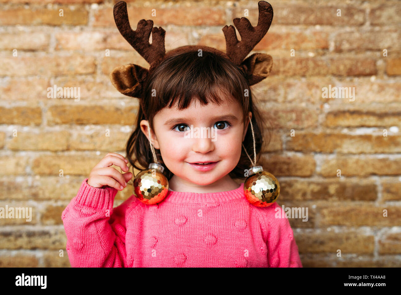 Ritratto di sorridente ragazza toddler indossando le renne palchi archetto e baubles di Natale Foto Stock