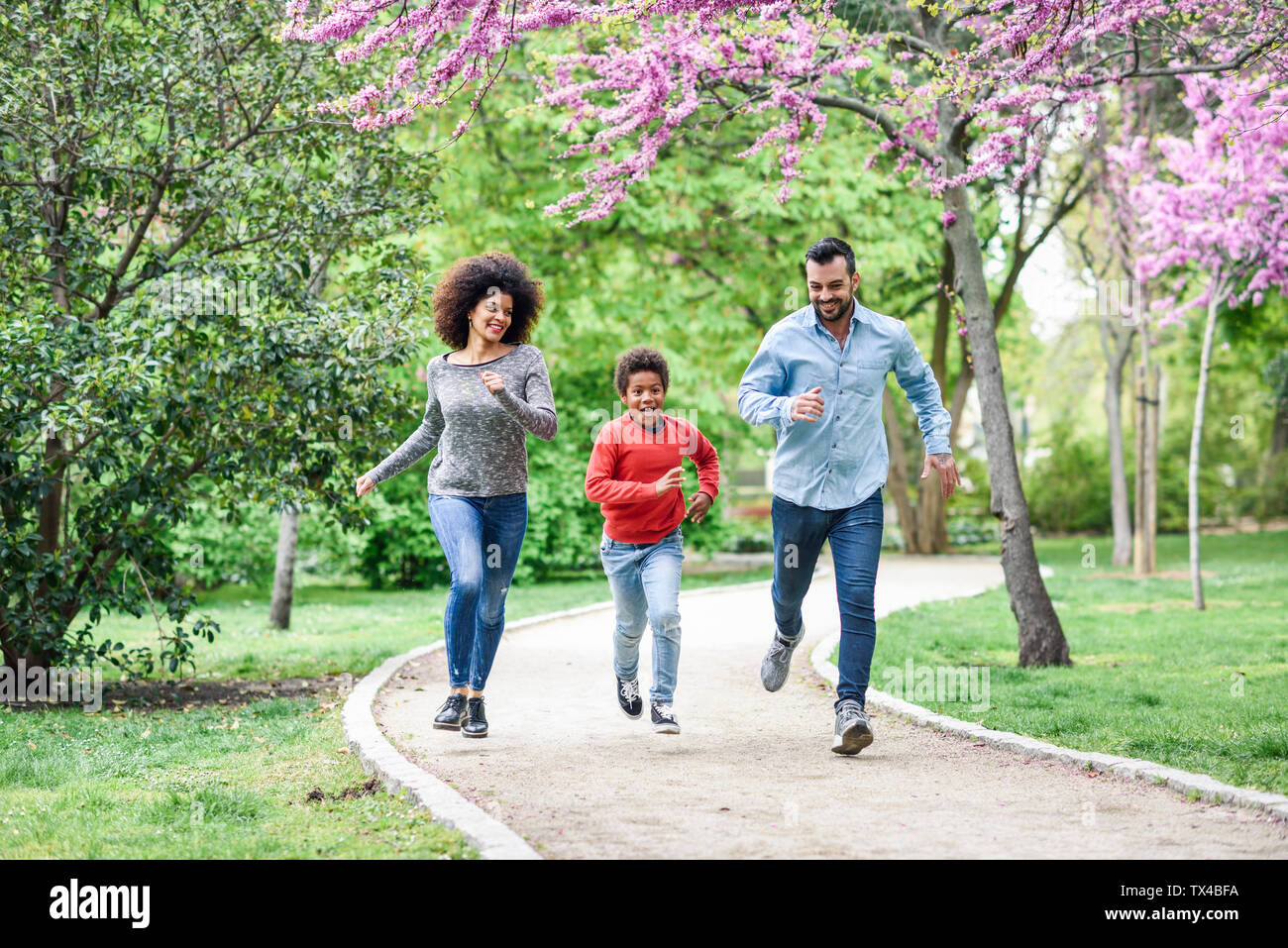 La famiglia felice correre e giocare in un parco Foto Stock