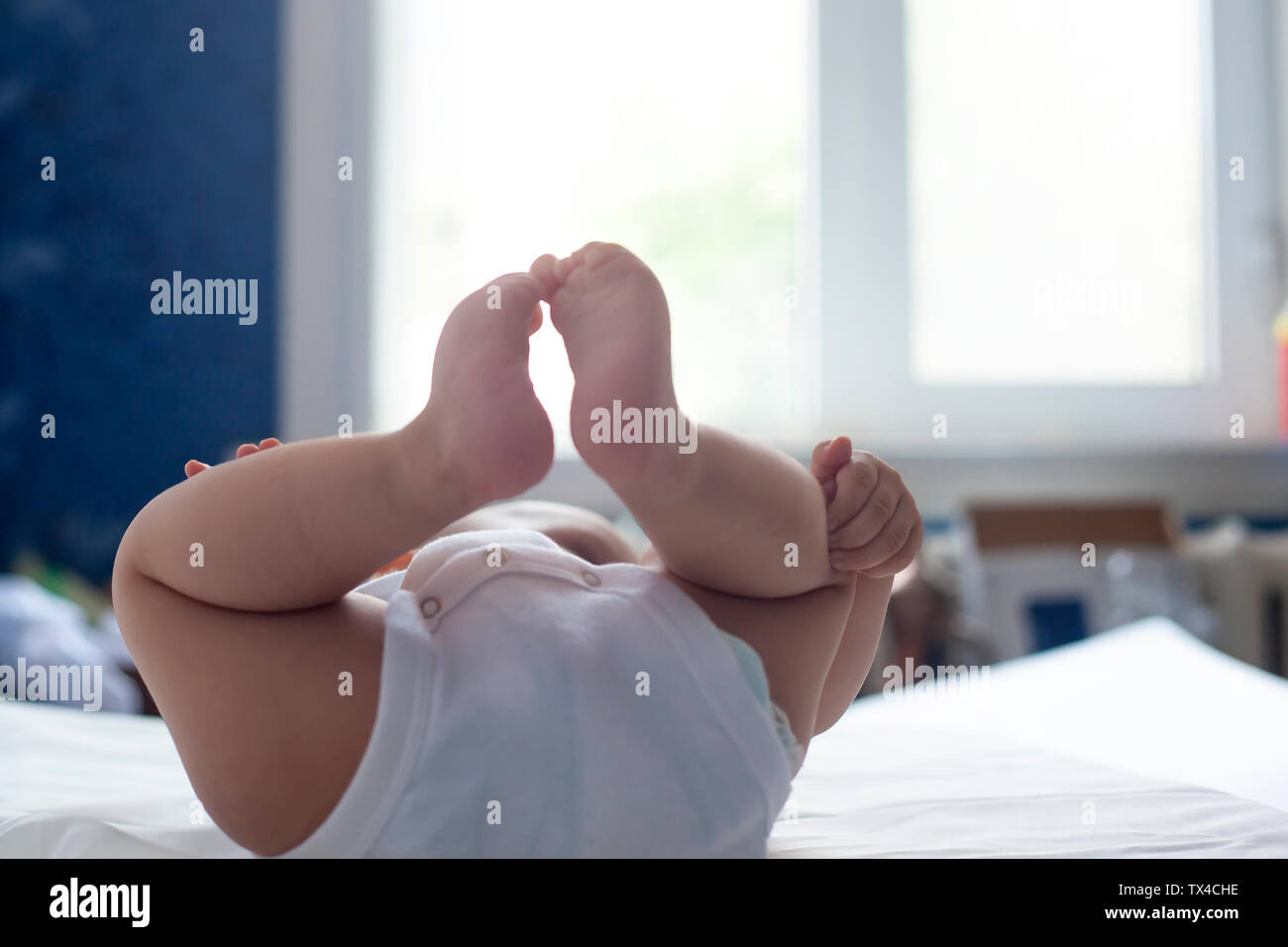 6-mese baby divertendosi in biancheria da letto bianca. Carino il bambino giacente sul letto. Famiglia, vita nuova concezione dell'infanzia. Foto Stock