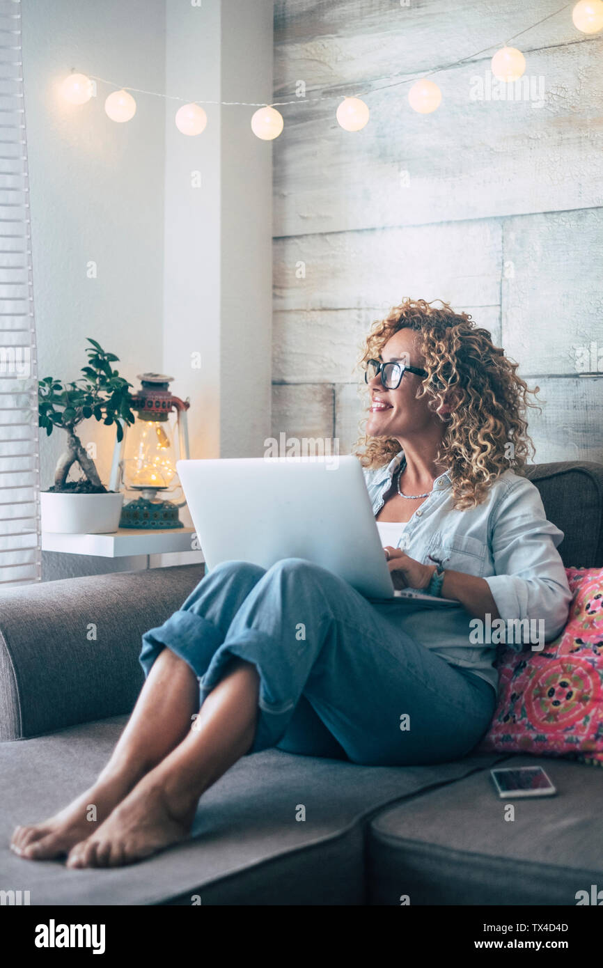 Donna che utilizza computer portatile sul lettino a casa Foto Stock