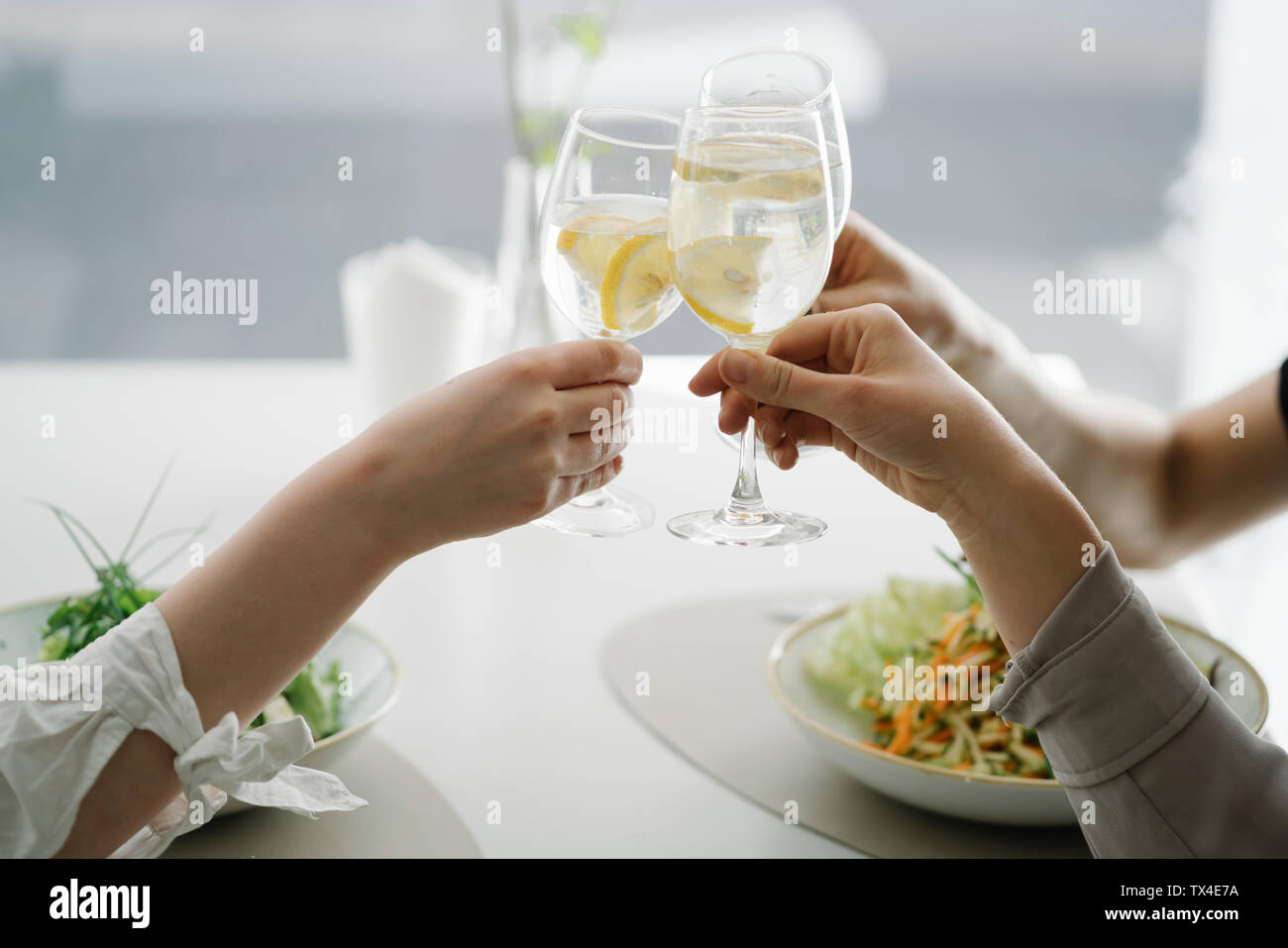 Close-up di tre donne la tostatura bicchieri di acqua in un ristorante Foto Stock