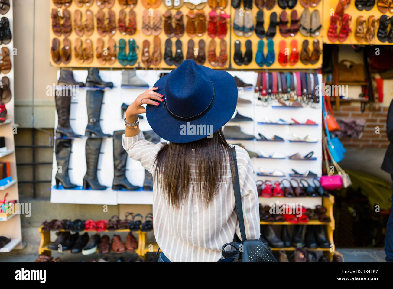 L'Italia, Firenze, vista posteriore del giovane turista la visione di offerta di prodotti in pelle sulla strada Foto Stock