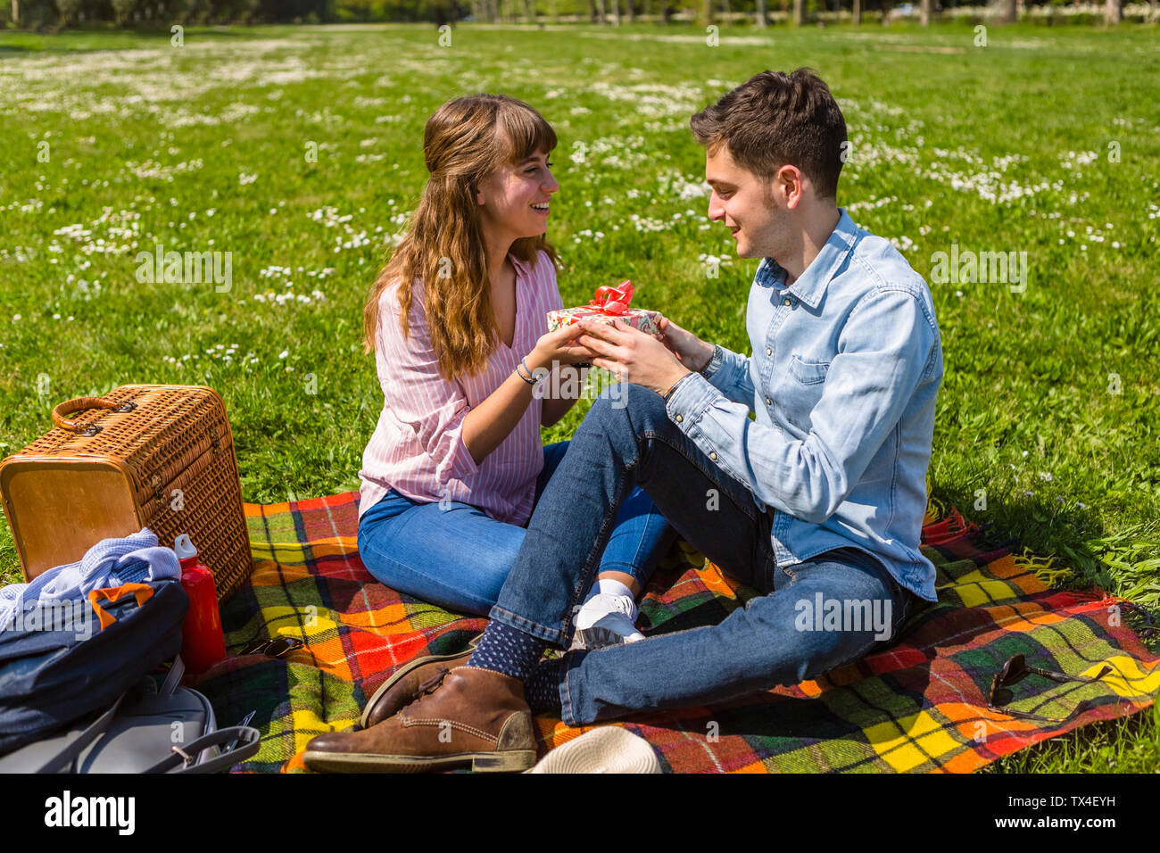 Giovane donna regalare il suo fidanzato con un presente in un parco Foto Stock
