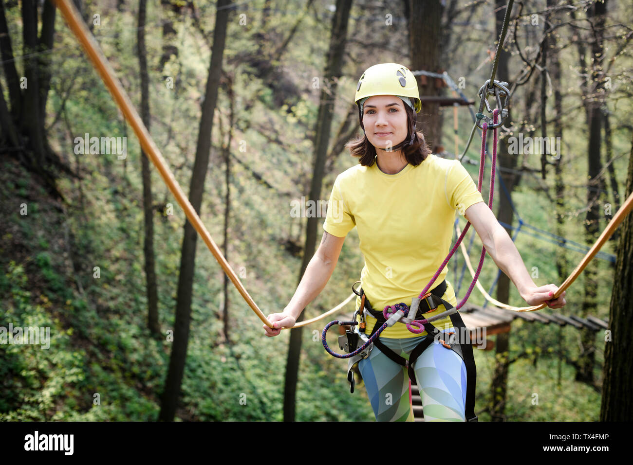 Giovane donna indossa giallo t-shirt e casco in un corso di corda Foto Stock