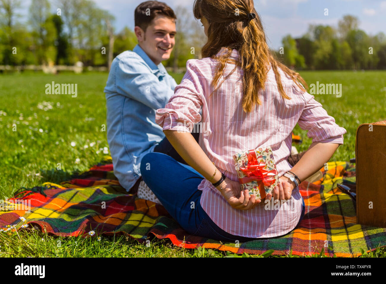 Giovane donna regalare il suo fidanzato con un presente in un parco Foto Stock