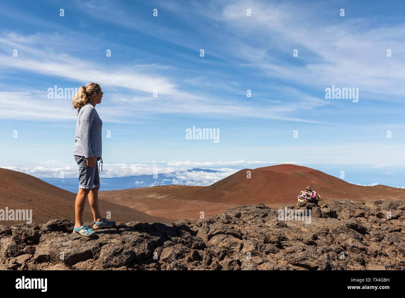 Stati Uniti d'America, Hawaii, Mauna Kea vulcano, turista femminile guardando a vista sul paesaggio vulcanico Foto Stock