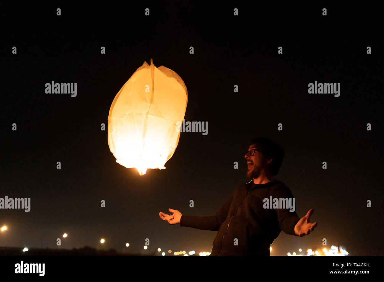 Uomo eccitato con galleggianti lanterna del cielo di notte Foto Stock